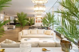 Heller Loungebereich mit weißen Sofas, großen Palmen und modernen Kronleuchtern