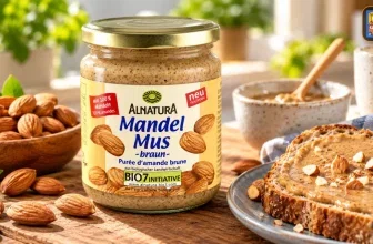 Glas Alnatura Mandelmus braun mit Toast und Mandeln auf Holzplatte