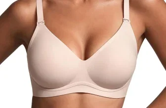 Model trägt einen hellbeigen, nahtlosen BH mit V-Ausschnitt und verstellbaren Trägern vor weißem Hintergrund.