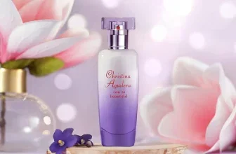 Parfümflasche von Christina Aguilera auf Korken mit violetten Blüten und pinker Blüte im Hintergrund