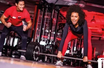 Mann und Frau trainieren mit Langhantel in einem Fitnessstudio mit roter Beleuchtung und clever fit Logo.