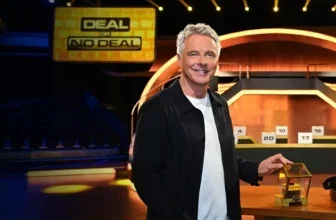 Moderator von Deal or No Deal im Studio mit goldenem Würfel und Telefon