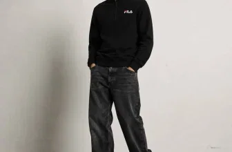 Model trägt schwarzes FILA Adam Retro 1/4-Zip Sweatshirt mit Logo und dunklen Jeans