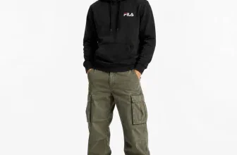 Mann in schwarzem FILA Hoodie, olivgrünen Cargohosen und grauen Sneakern vor weißem Hintergrund