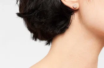 Profilansicht einer Frau mit kurzem dunklen Haar und einem kleinen rosenfarbenen Ohrring.