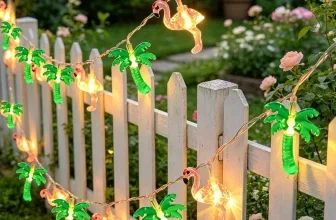 Lichterkette mit Flamingo- und Palmen-LEDs an einem weißen Gartenzaun