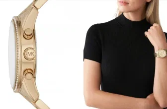 Goldfarbene Michael Kors Damenuhr im Detail und getragen von einer Frau in schwarzem Oberteil