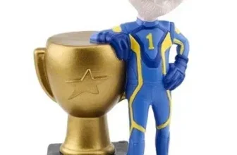 Figur von Ed in blau-gelbem Rennanzug neben goldenem Pokal mit Stern und Plakette