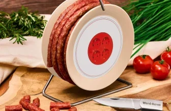 Wurstkabeltrommel auf Holzbrett mit Messer, Tomaten und Kräutern