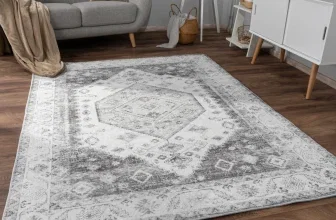 Grau-weißer Teppich mit geometrischem Muster auf dunklem Holzboden im Wohnzimmer