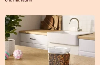 Klarer Behälter mit würfelförmigen Katzenleckerlis auf einer Holztheke in einer Küche