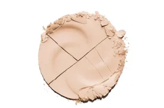 Rissiges, beige-cremefarbenes Puder in runder Form auf weißem Hintergrund