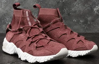 Weinrote ASICS Sneaker mit weißer Sohle auf dunklem Betonboden