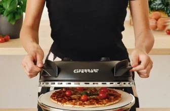 Person öffnet den Deckel eines schwarzen G3 Ferrari Pizzaofens mit einer Pizza darin