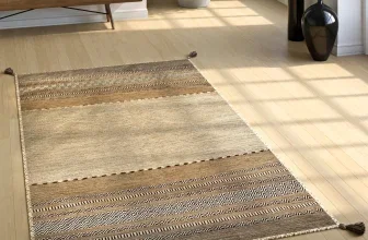Handwebteppich mit geometrischen Mustern in Beige und Braun auf hellem Holzboden