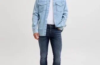 Mann in dunkelblauer Jeans und hellem Denimhemd mit braunen Schuhen im Studio