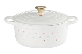 Weißer Le Creuset Bräter mit rosafarbenen Herzchen und goldener Deckelknauf