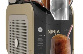Ninja SLUSHi Maschine in Gold mit Glas, das ein braunes Slush-Getränk mit Strohhalm enthält.