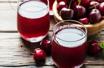 Glas mit rotem Kirschsaft und frischen Kirschen auf rustikalem Holztisch