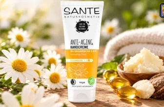 SANTE Handcreme-Tube auf Holz neben Kamillen, Walnuss und Kapseln