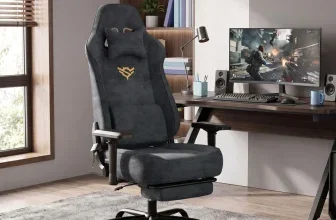 Grauer Gamingstuhl mit Fußstütze und Nackenkissen in einem Home-Office neben einem Schreibtisch mit Monitor.